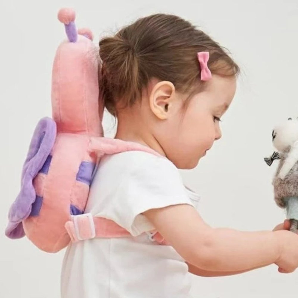A toddler playing while wearing the Pink Bee Bibbito Head Cushion like a tiny backpack